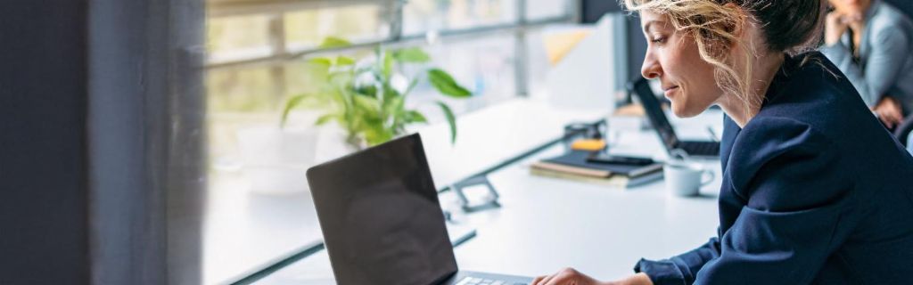 Млада жена работи на лаптоп во модерна канцеларија.