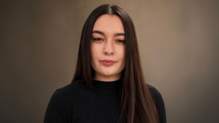 Daniela Moaca, Senior Manager IT во EOS Romania, портретна фотографија со темен пуловер со висока јака.