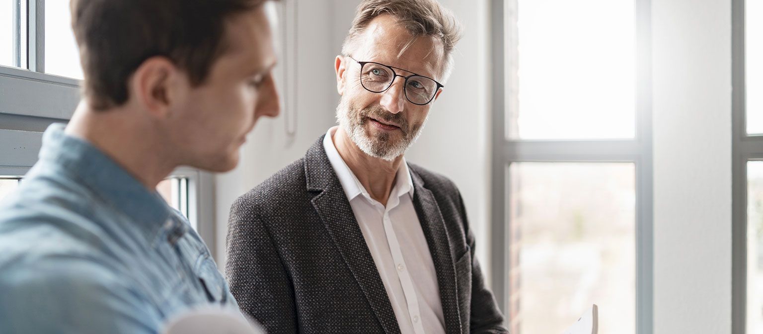 Двајца мажи во канцеларија разговараат за резултатите од студијата „Европски платежни практики 2025“ на ЕОС Групацијата за дигитализација во управувањето со побарувањата.